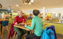 Zwei Frauen essen an einem Hochtisch in einem Restaurant | © Bergbahnen Flumserberg AG